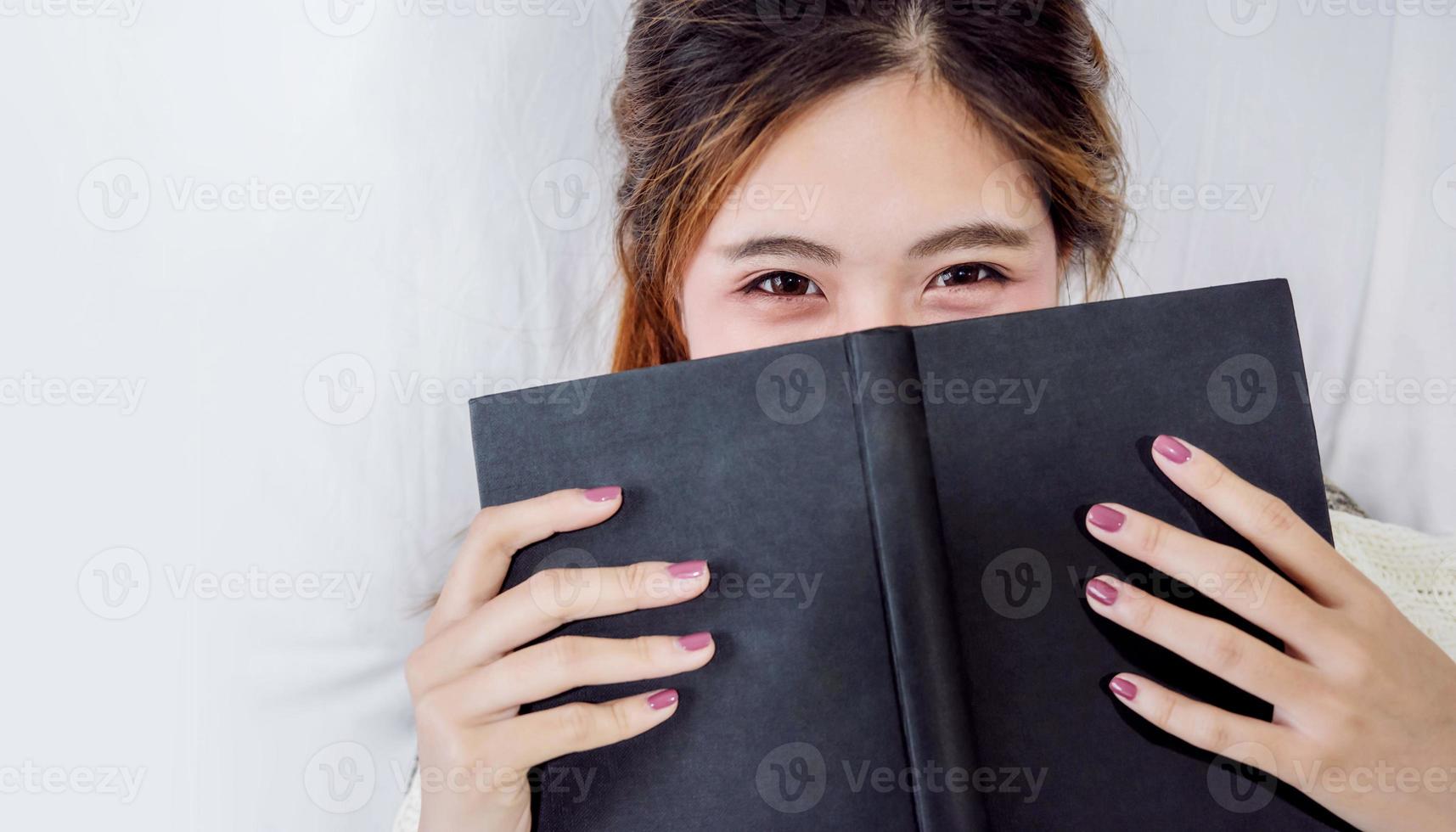 Woman Reading on Bed. Looking at Camera with Charming Eyes. Top View photo