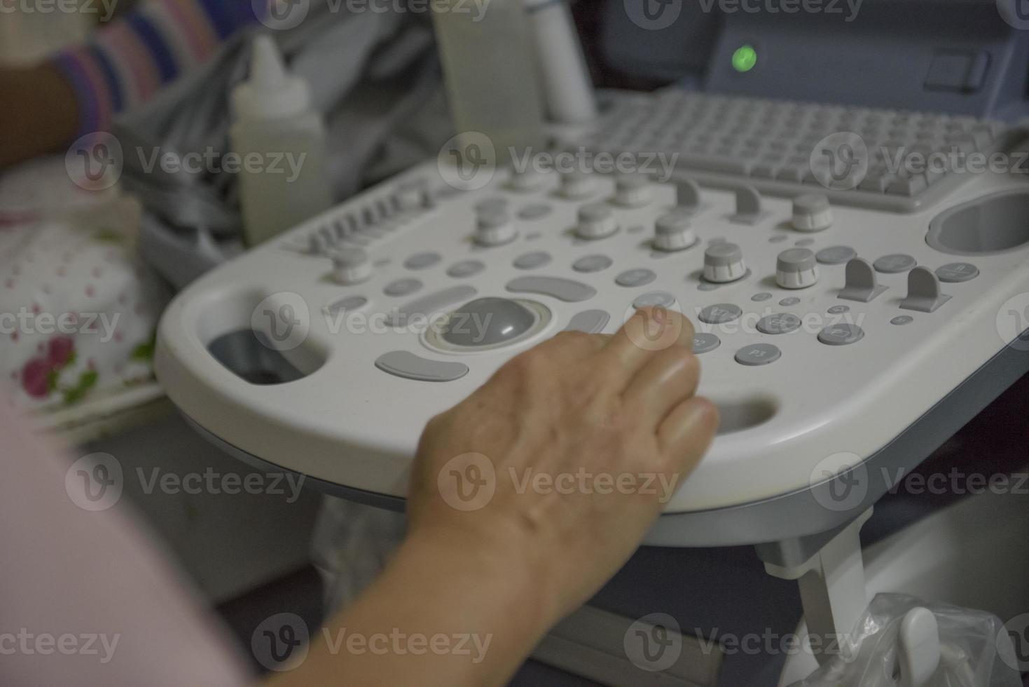 máquina de ultrasonido hay una mano en el panel de control. el personal médico realiza ecografías de mujeres embarazadas. foto