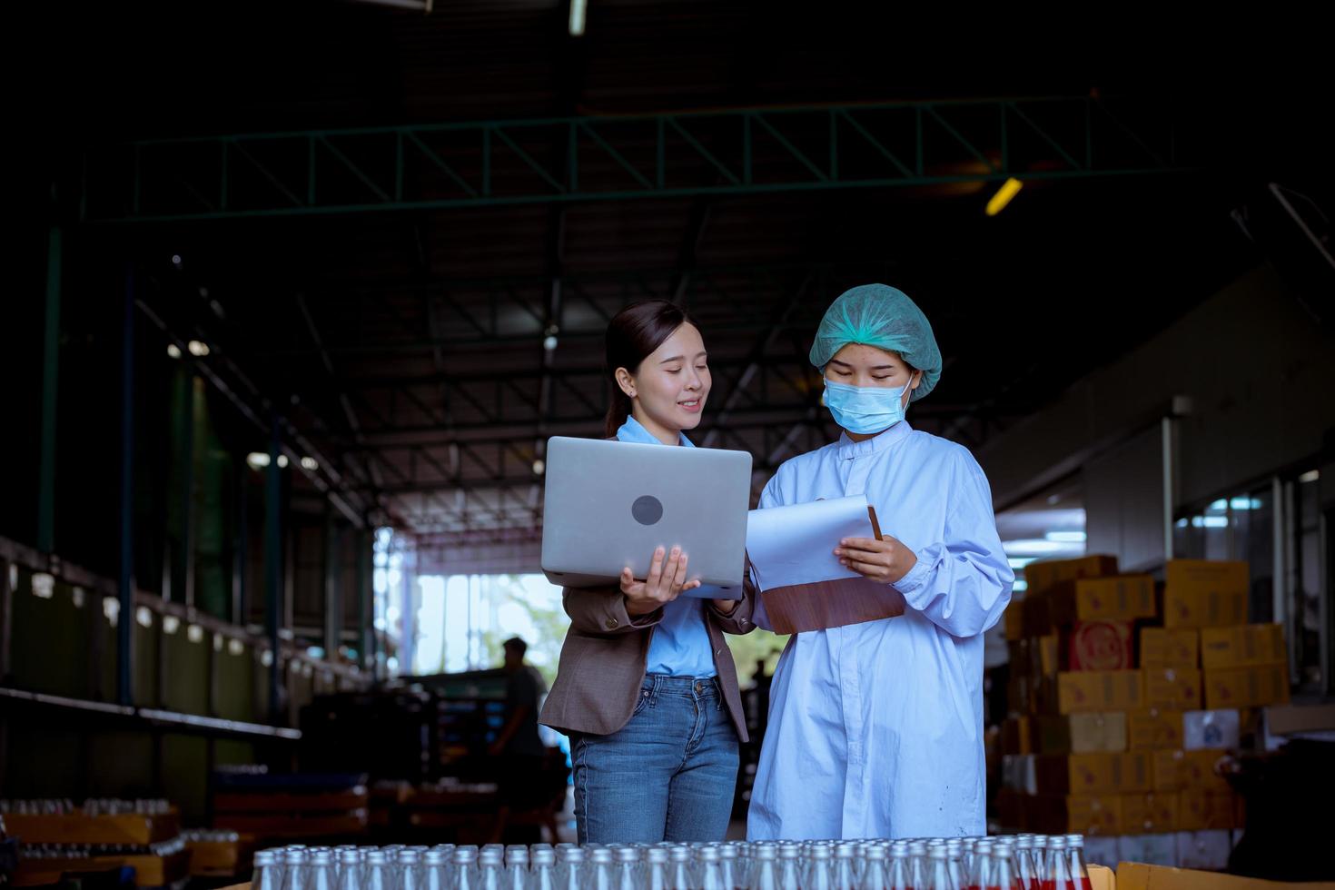 Worker of science in bottle beverage factory wearing safety hat posing show work to check quality of Basil seed produce on conveyer belt before distribution to market business. photo