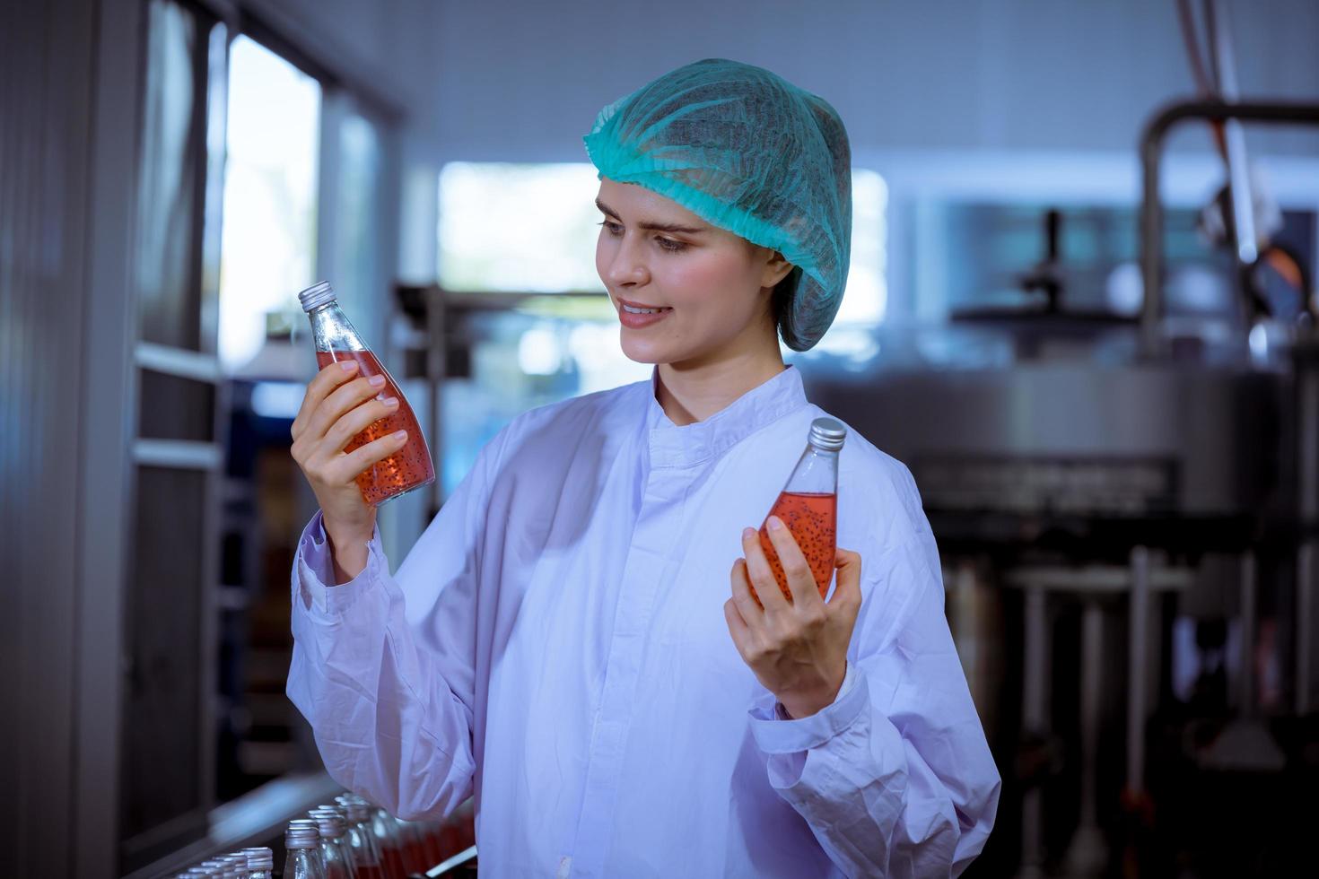 Worker of science in bottle beverage factory wearing safety hat posing show work to check quality of Basil seed produce on conveyer belt before distribution to market business. photo