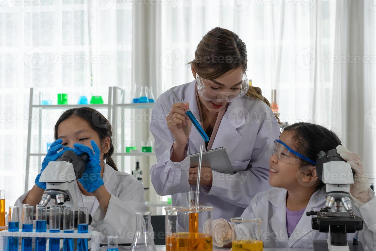 Children Using Microscope to Learn Microbiology and Science in Laboratory with Teacher photo