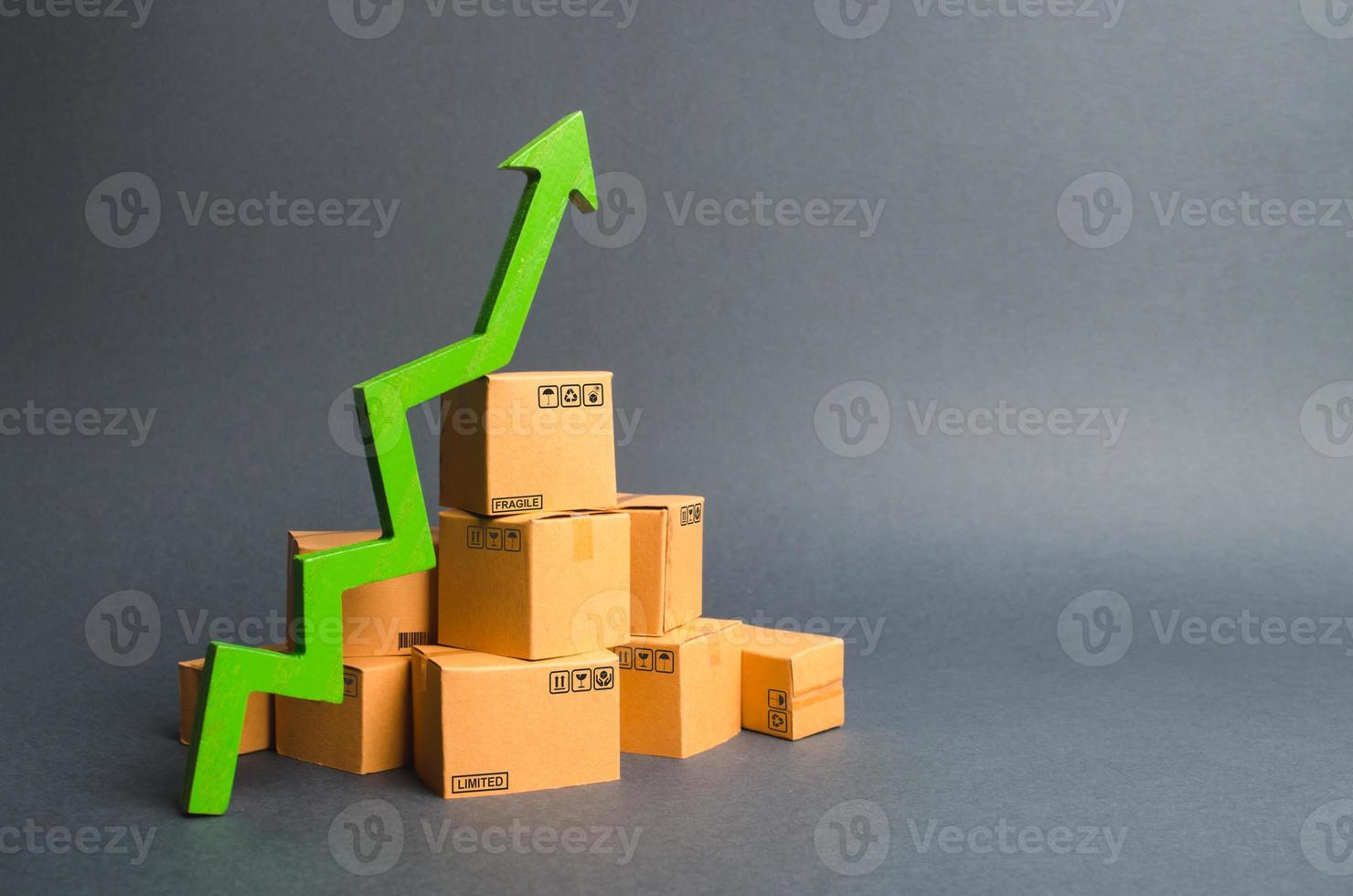 A pile of cardboard boxes and a green up arrow. The growth rate of production of goods and products, increasing economic indicators. Increasing consumer demand, increasing exports or imports. photo