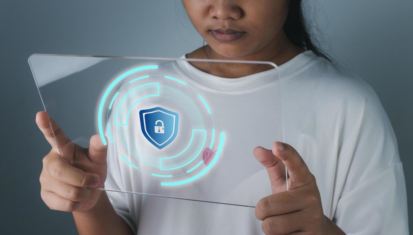 Woman holding phone tablet screen with protection icon. Represents protection against external hacks. Security concepts against code, virus, firmware and malware. photo