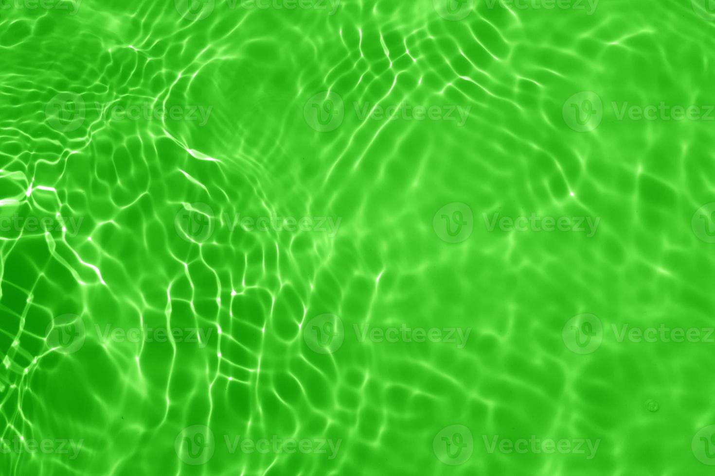 desenfoque borroso transparente color verde claro agua tranquila textura superficial con salpicaduras, burbujas. fondo de ondulación de agua púrpura brillante. superficie del agua en la piscina. brillo de agua de burbuja verde. foto