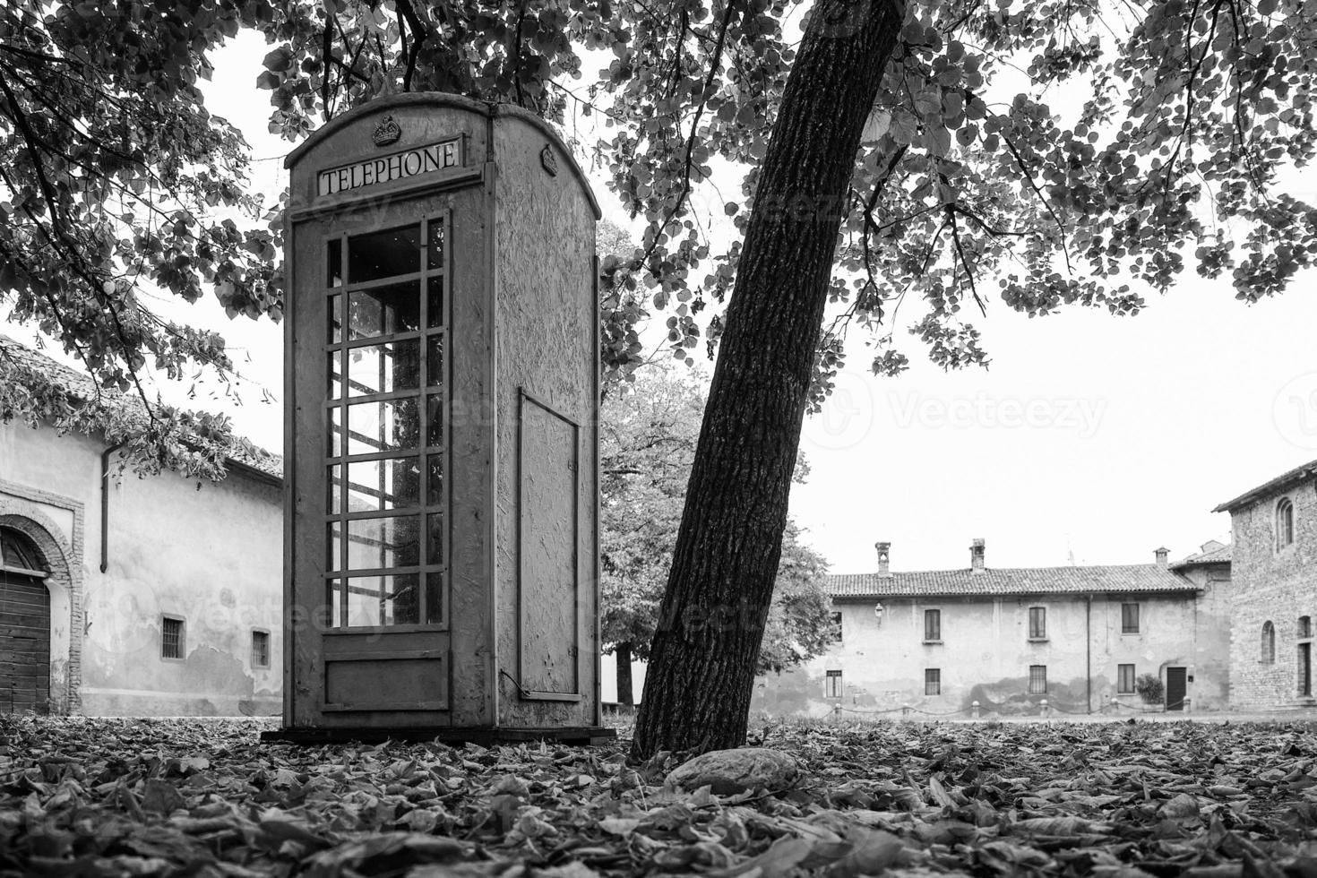 Unrelated english Phone box in an old italian village Concept of communication and unrelated object photo