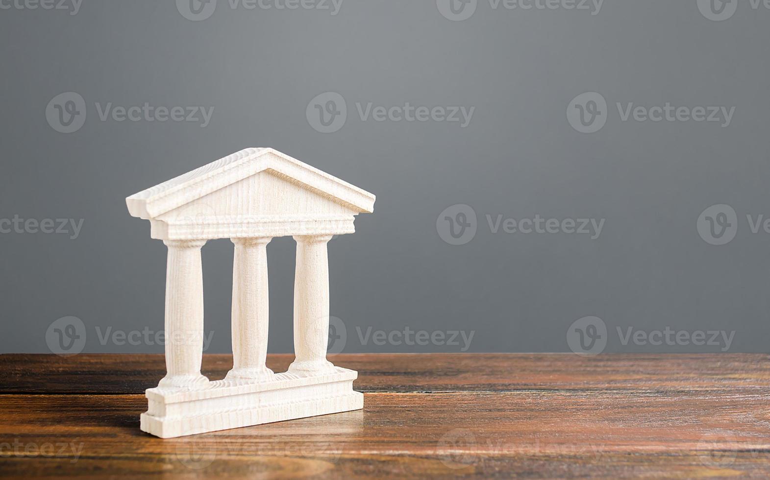 White building figurine with pillars in antique style. Concept of city administration, bank, university, court or library. Architectural monument in old town part . Banking, education, government. photo