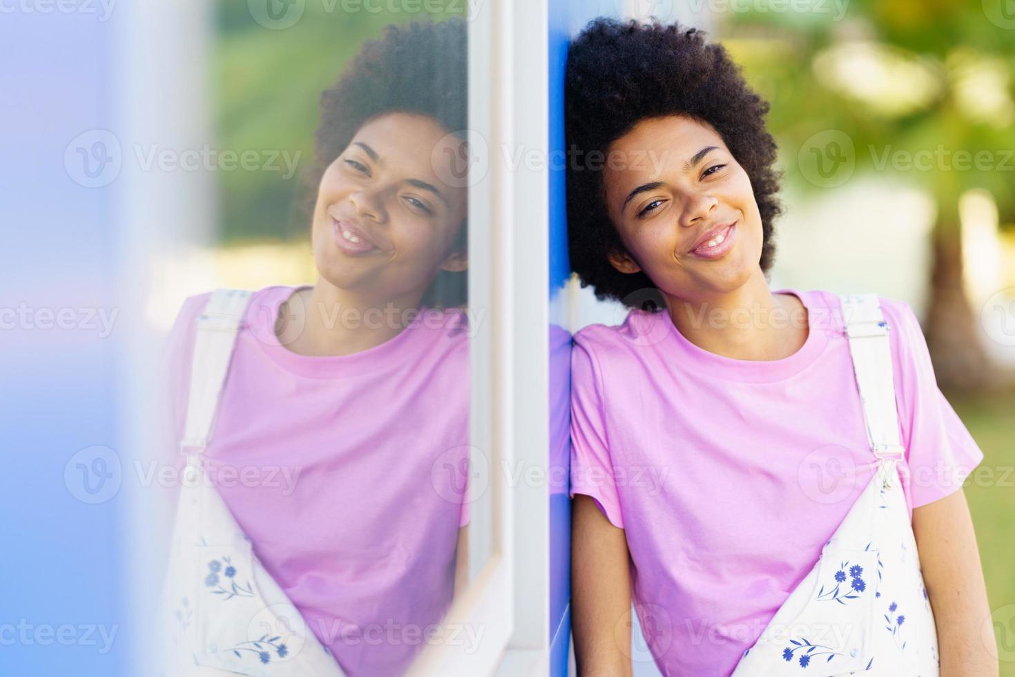 Positive black woman standing near building photo