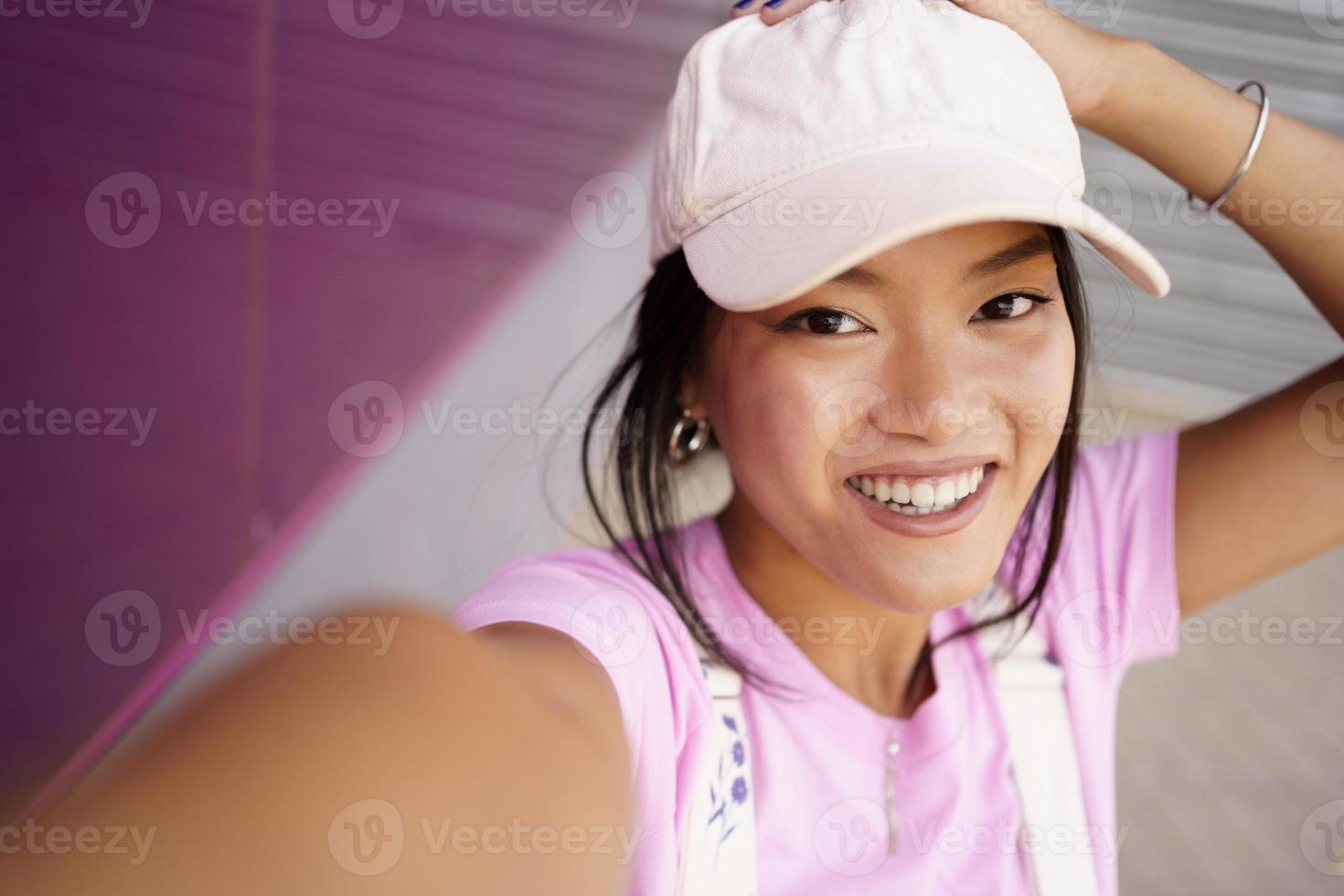 Asian girl taking a photo or video selfie with her smartphone, to post
