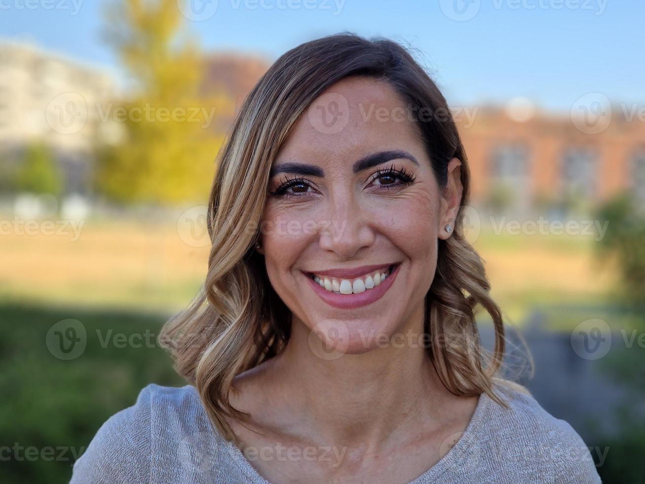 feliz mujer de mediana edad en un parque urbano. mujer atractiva sonriendo a la cámara. foto