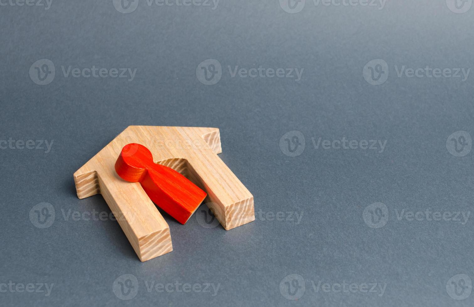 Red figurine of a man and a fallen house on a gray background. Concept of accident or disaster. The consequences of the war, the collapse of the building. Life and property insurance photo