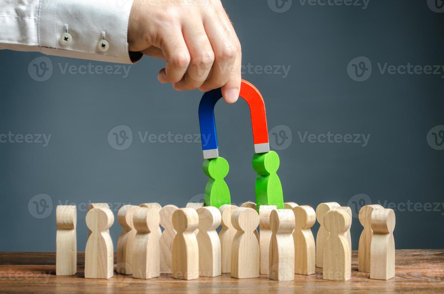 Businessman with a magnet pulls green figures of people out of the crowd. Recruiting new workers. Formation of a new business team of applicants. Search talented workers with great career potential photo