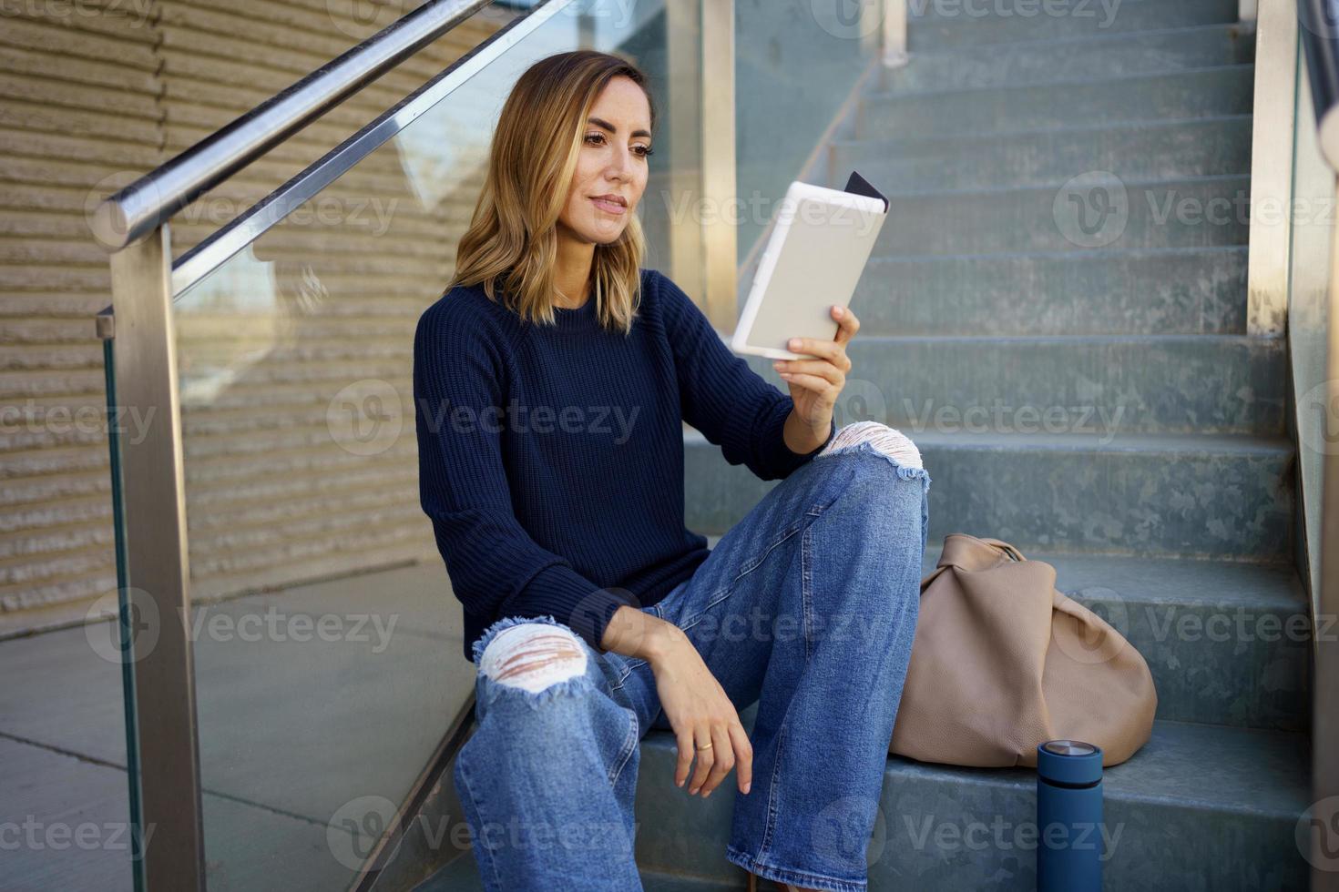 mujer de mediana edad leyendo con su libro electrónico en un descanso para tomar café cerca de su oficina. foto