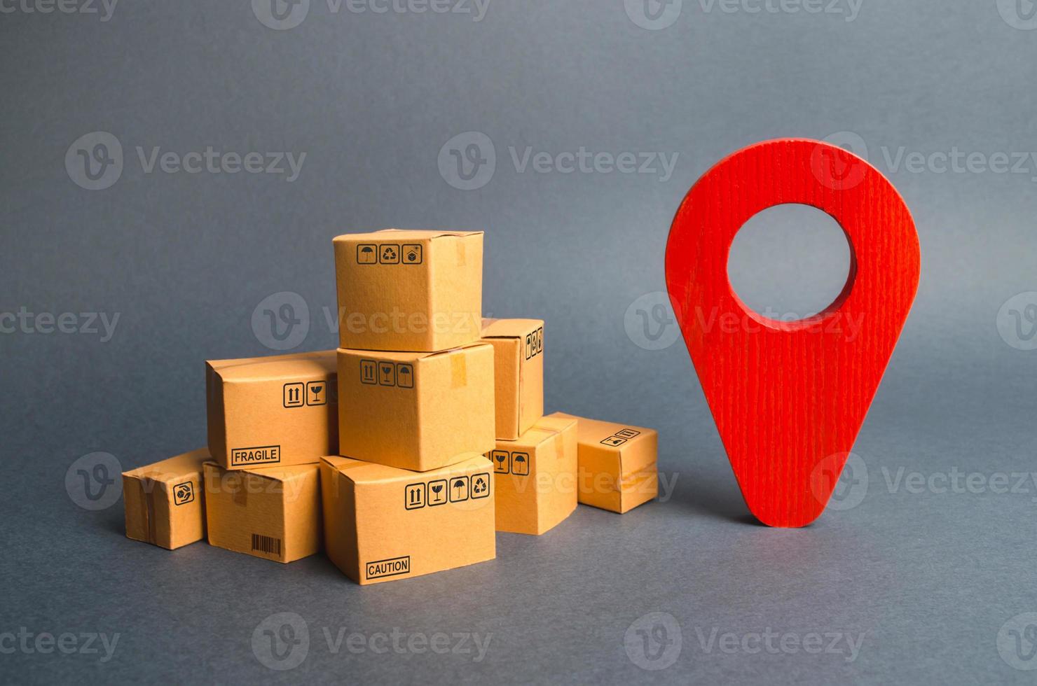 A pile of cardboard boxes and a red position pin. Locating packages and goods. Algorithm for constructing a minimum route for the delivery of orders. Tracking parcels via the Internet. photo