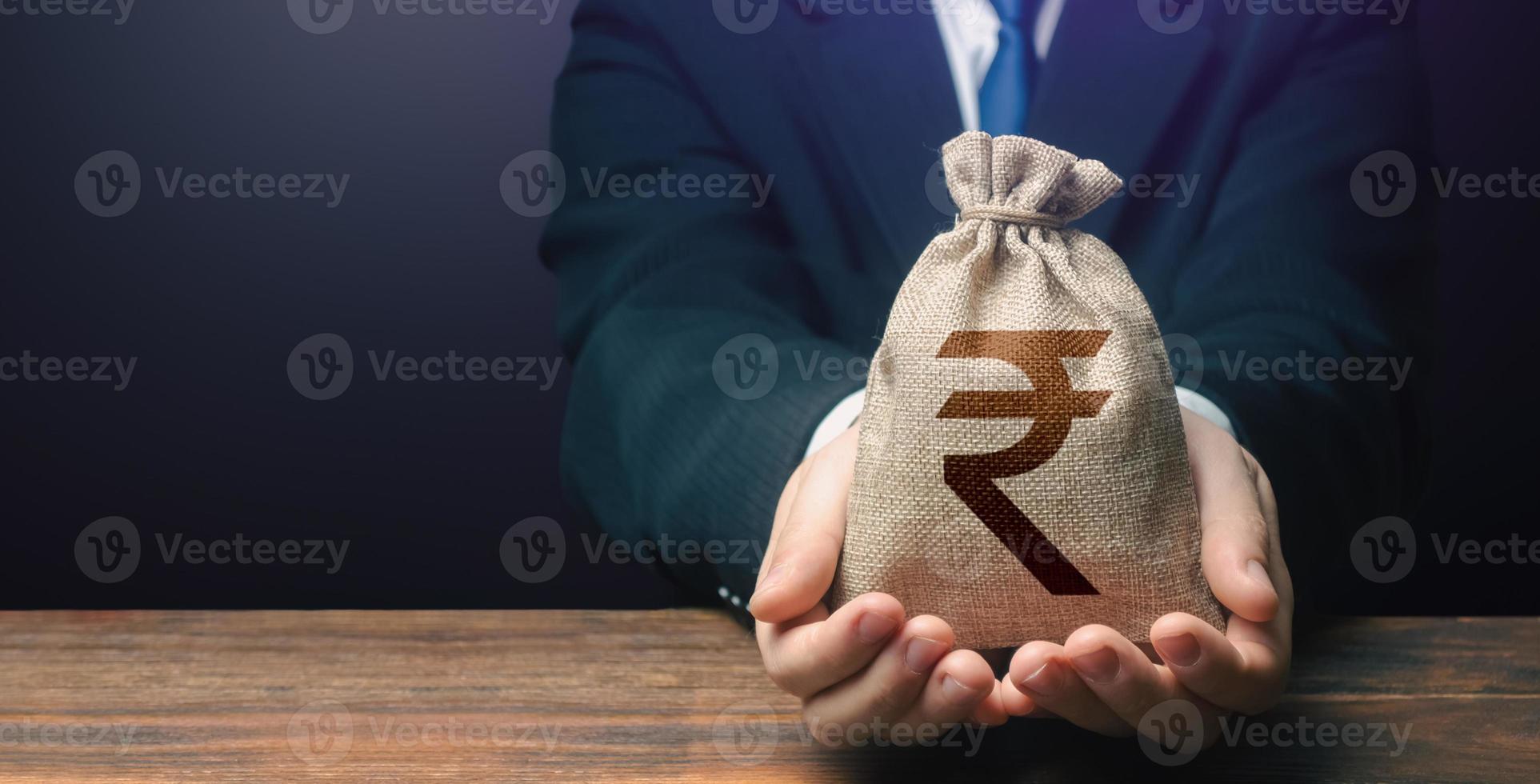 Businessman holds out indian rupee money bag. Getting a grant