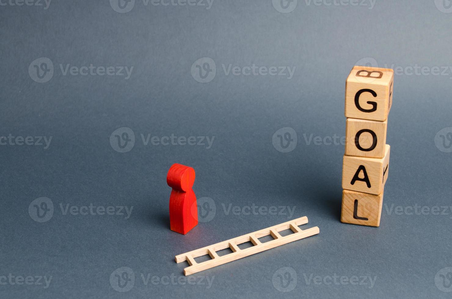 tower of cubes with an inscription goal and a red figure of a man stands near fallen ladder. concept of achieving the goal, subject to the application of all the efforts and desires. Tool for success. photo