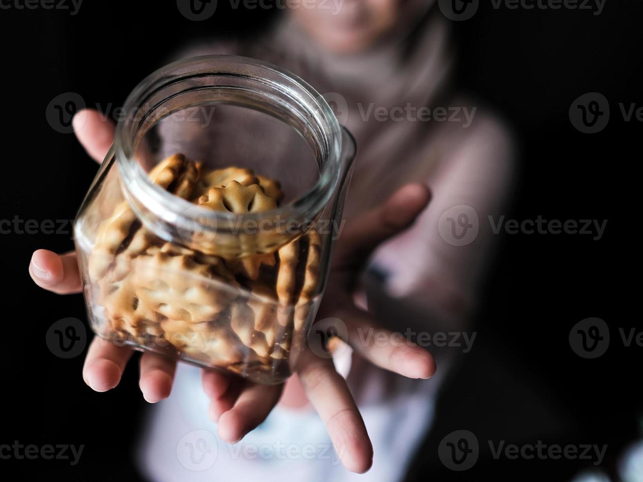 Close-up view of a woman holding a glass jar of cookies photo