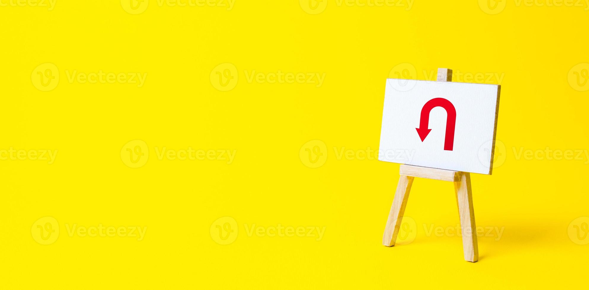 Easel with arrow turning back. Change plans, circumstances. Tactical retreat. Avoiding problems, reducing risks. Find other way. Return to source. Step back. Break a promise. Reassessment of actions photo