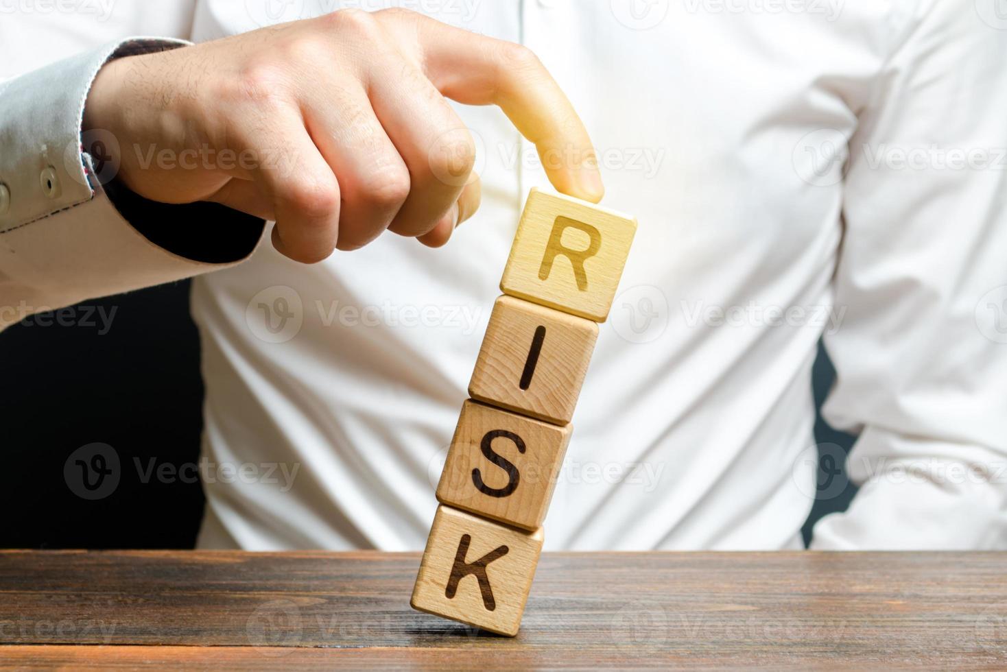 Businessman rescues with his finger a tower of cubes with the word Risk from falling Risk management, cost assessment, business and investment safety. Strengthen business resilience and flexibility. photo