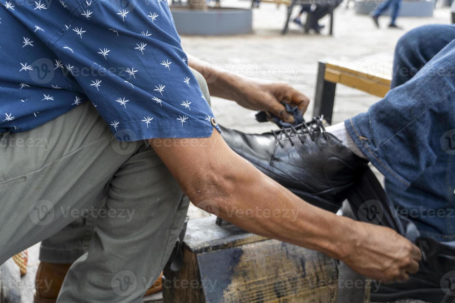 older latino man, dark skinned, cleaning and shining shoes, happy with his profession mexico photo