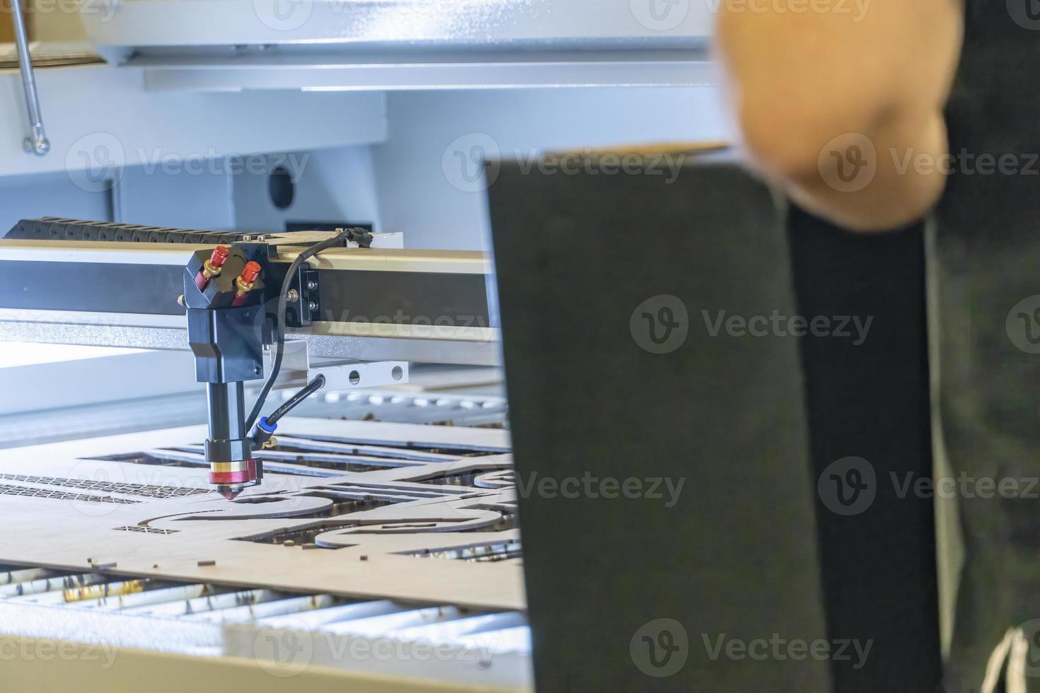 laser cutting machine, cutting wood sheets, while a man takes care of the process, latin america photo