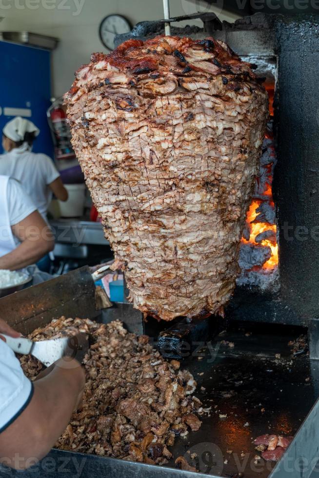 comida mexicana trompo pastor tacos al pastor, carne apilada en salsa con especias foto