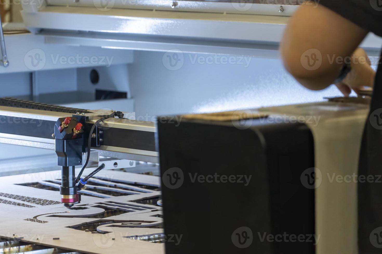 laser cutting machine, cutting wood sheets, while a man records the process, mexico photo