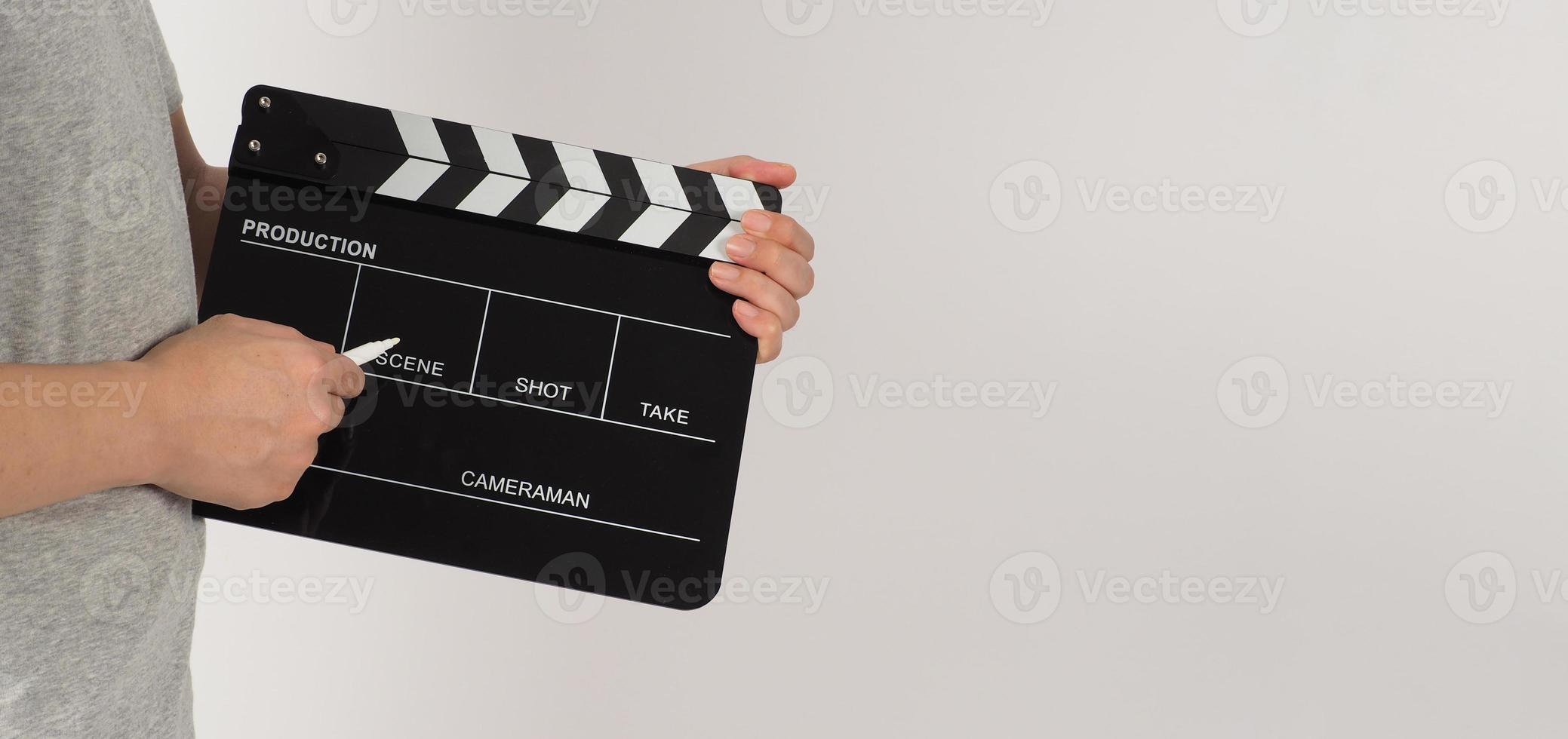The hand is holding a black clapper board and marker Pen on white background. photo