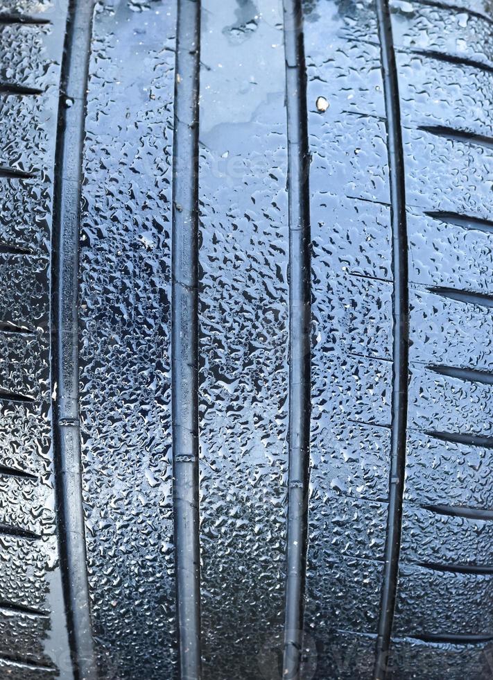 Black big tires in a close up view with water drops. Tire tread problems. photo