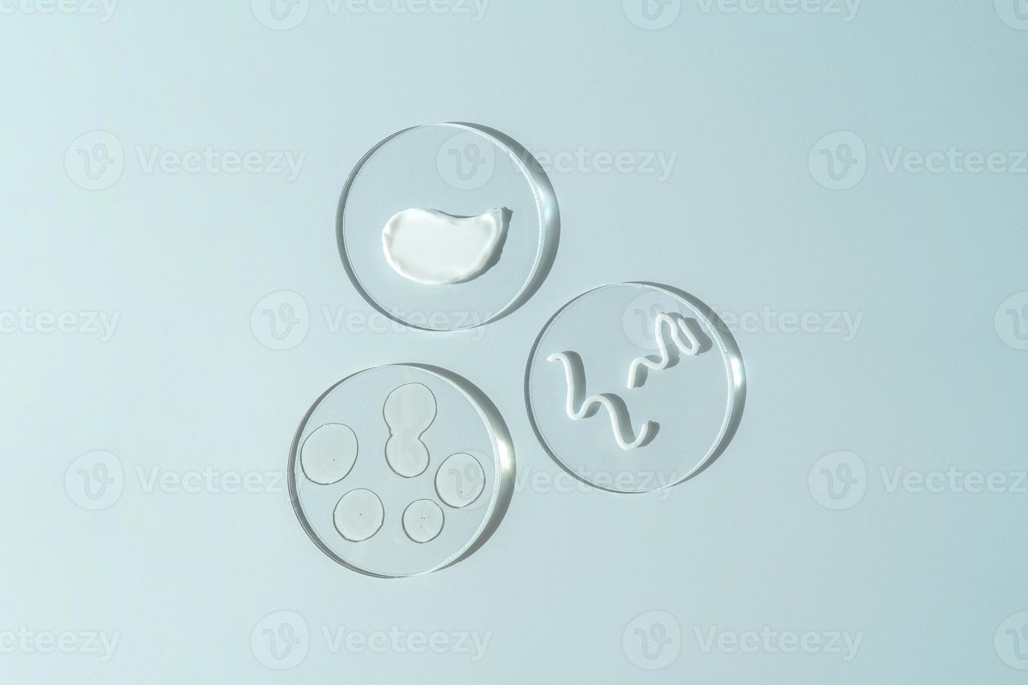 A transparent face serum or oil with drops and a white smudge of face cream on a round podiums. Cosmetology and pharmaceuticals concept. photo