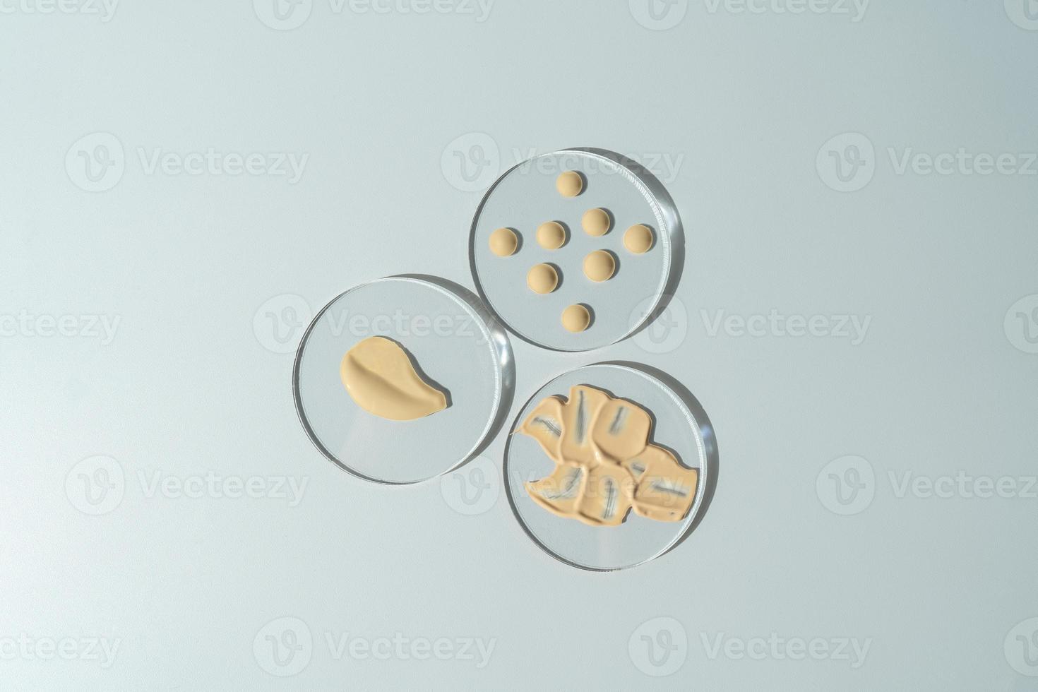 Face tonal cream smudge and drops lying on glass plates. Cosmetology and makeup concept photo