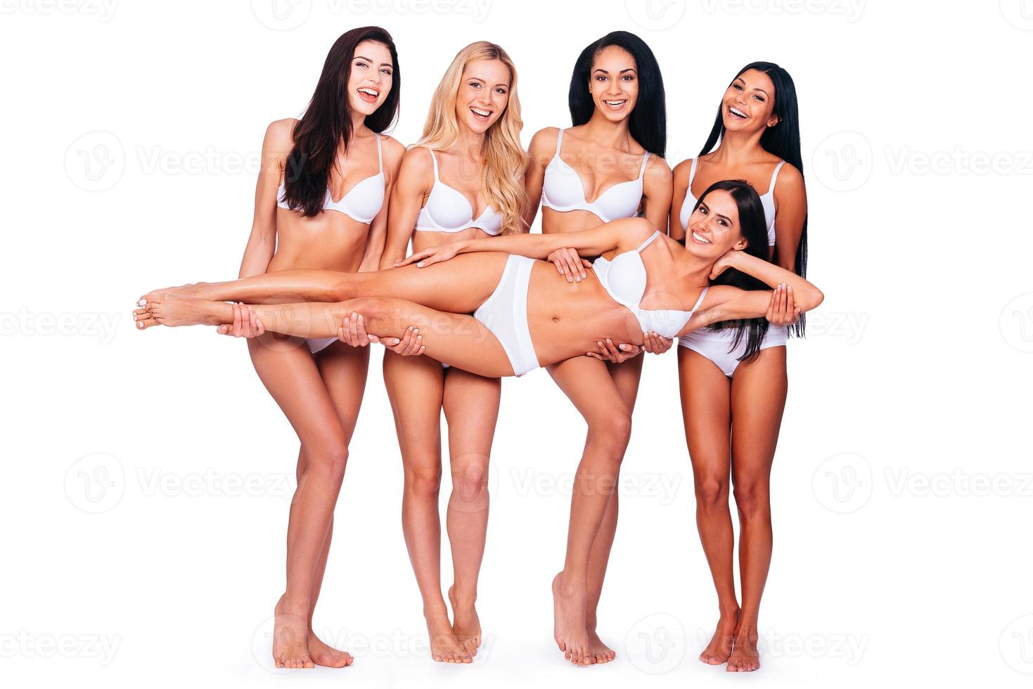 Carrying with fun. Full length of four cheerful women in lingerie carrying another one beauty and smiling while posing against white background photo