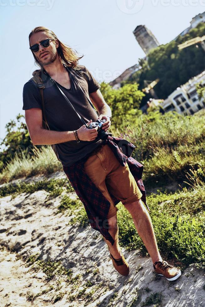 Searching for new direction. Full length of young man in casual clothing going somewhere while walking on the hill outdoors photo