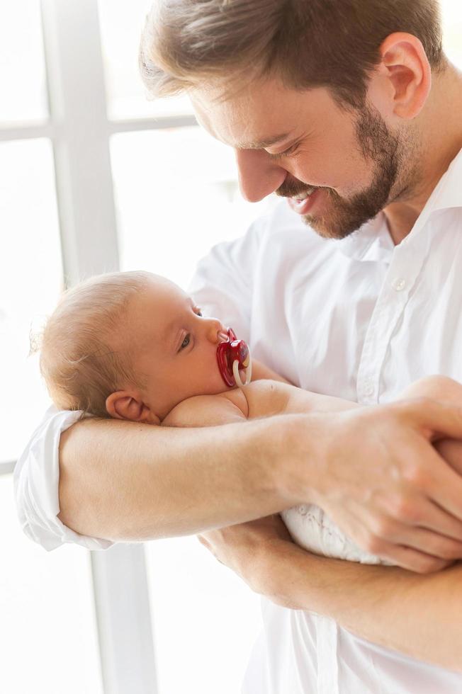 Father and baby. Close-up of father holding cute little baby in hands and smiling photo