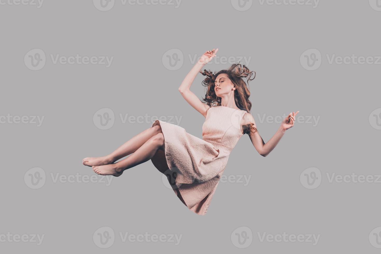 Falling in motion. Studio shot of attractive young woman hovering in air photo