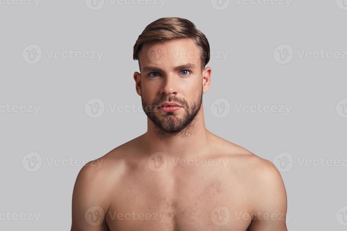 Just the way he is. Handsome young man looking at camera while standing against grey background photo