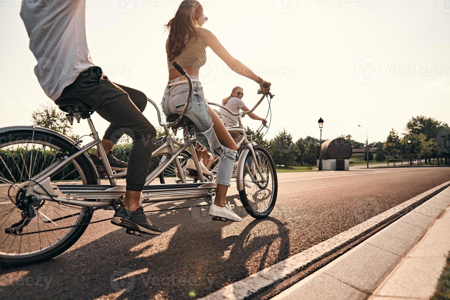 El mejor día para andar en bicicleta. grupo de jóvenes con ropa informal andando en bicicleta juntos mientras pasan tiempo sin preocupaciones al aire libre foto