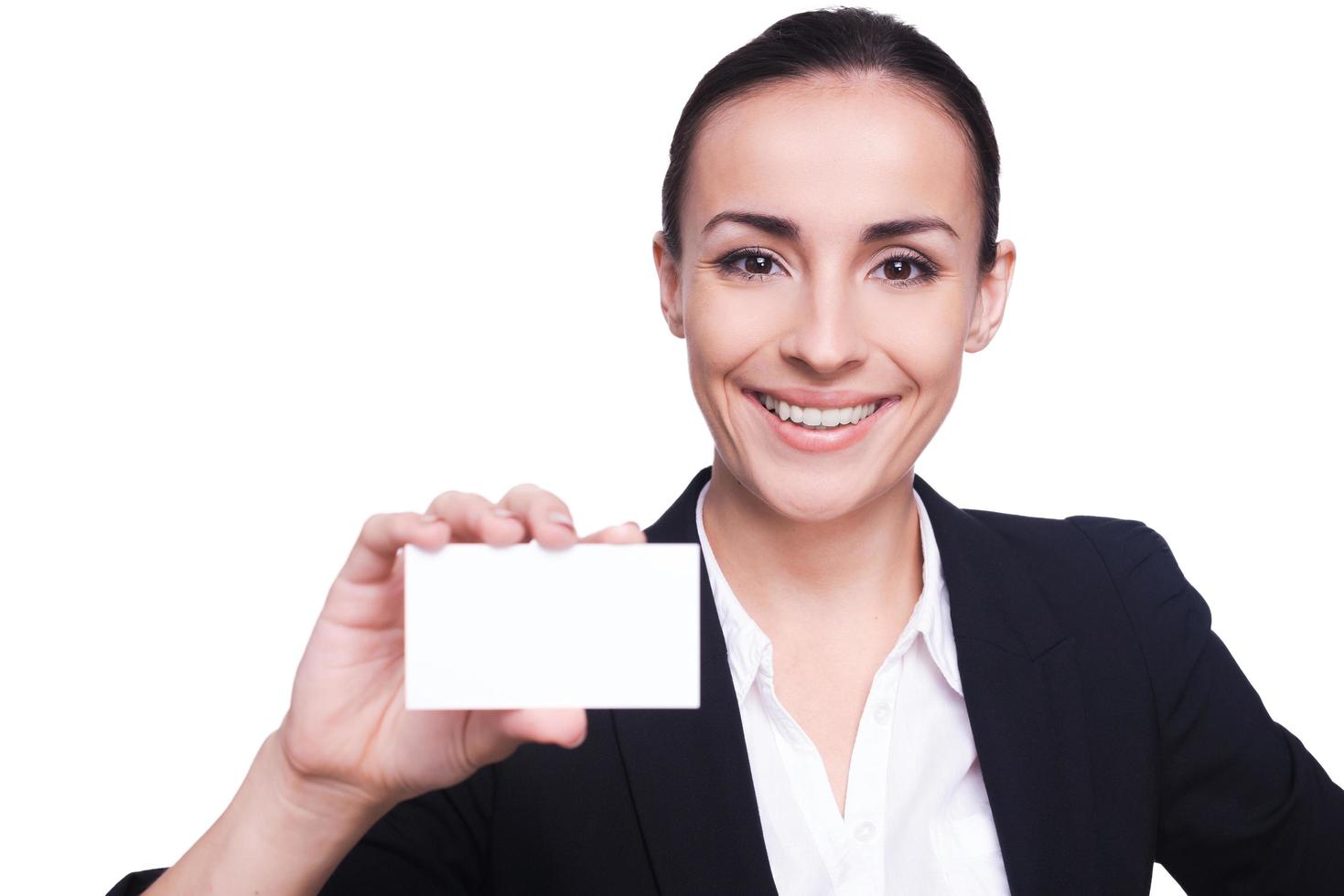 mujer con tarjeta de visita. hermosa mujer joven en ropa formal estirando su tarjeta de visita y sonriendo mientras está de pie aislado en blanco foto