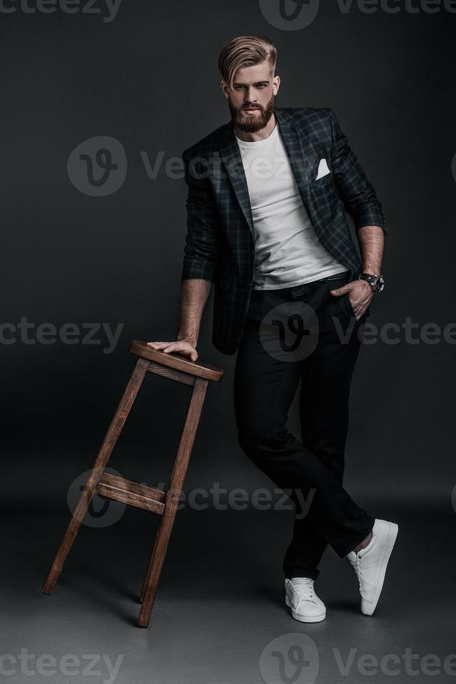 Confident and handsome. Full length of young man looking at camera while posing against grey background photo