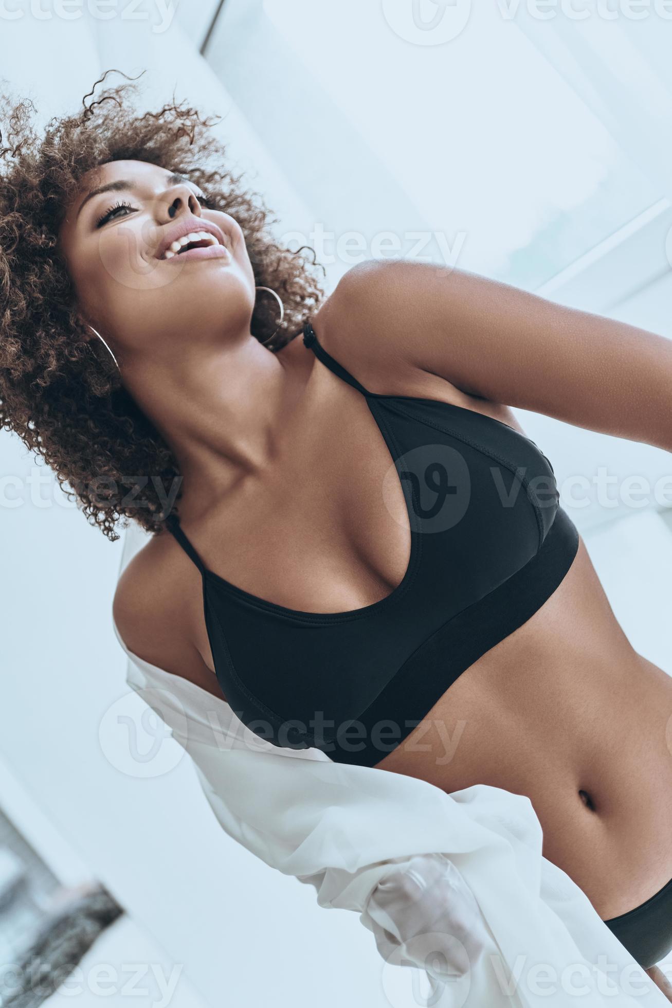 Pure beauty. Attractive young African woman in black lingerie smiling while  standing near the window at home 13572533 Stock Photo at Vecteezy