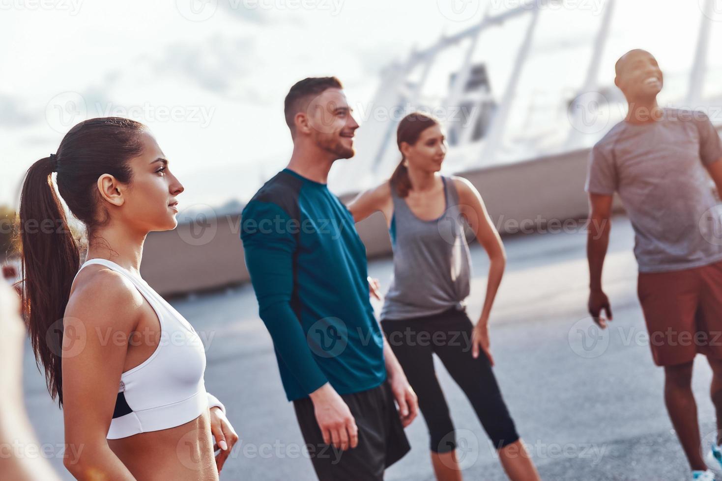 Group of people in sports clothing warming up and stretching outdoors photo