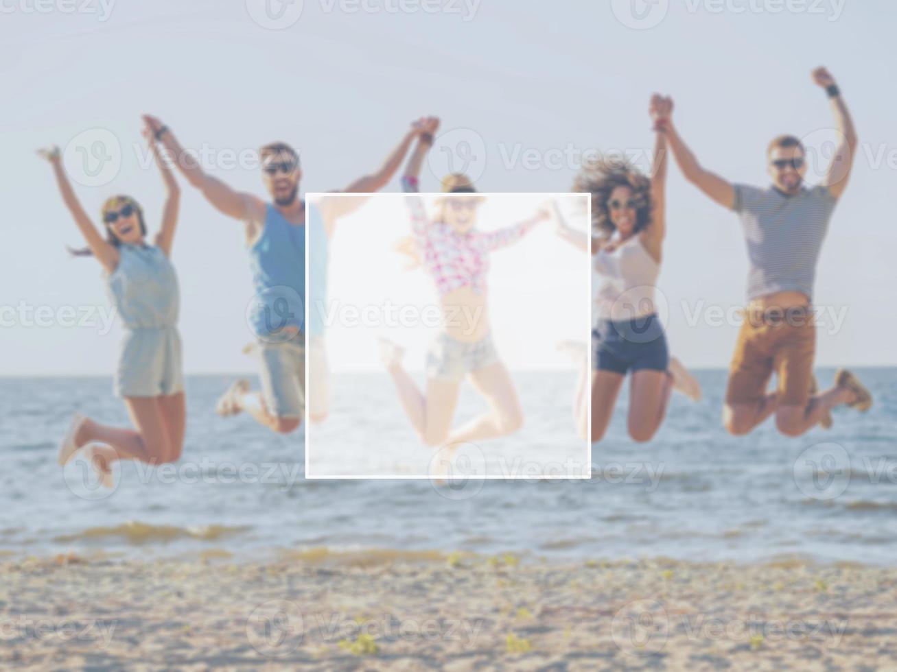 Fun with friends. Group of happy young people holding hands and jumping with sea in the background photo