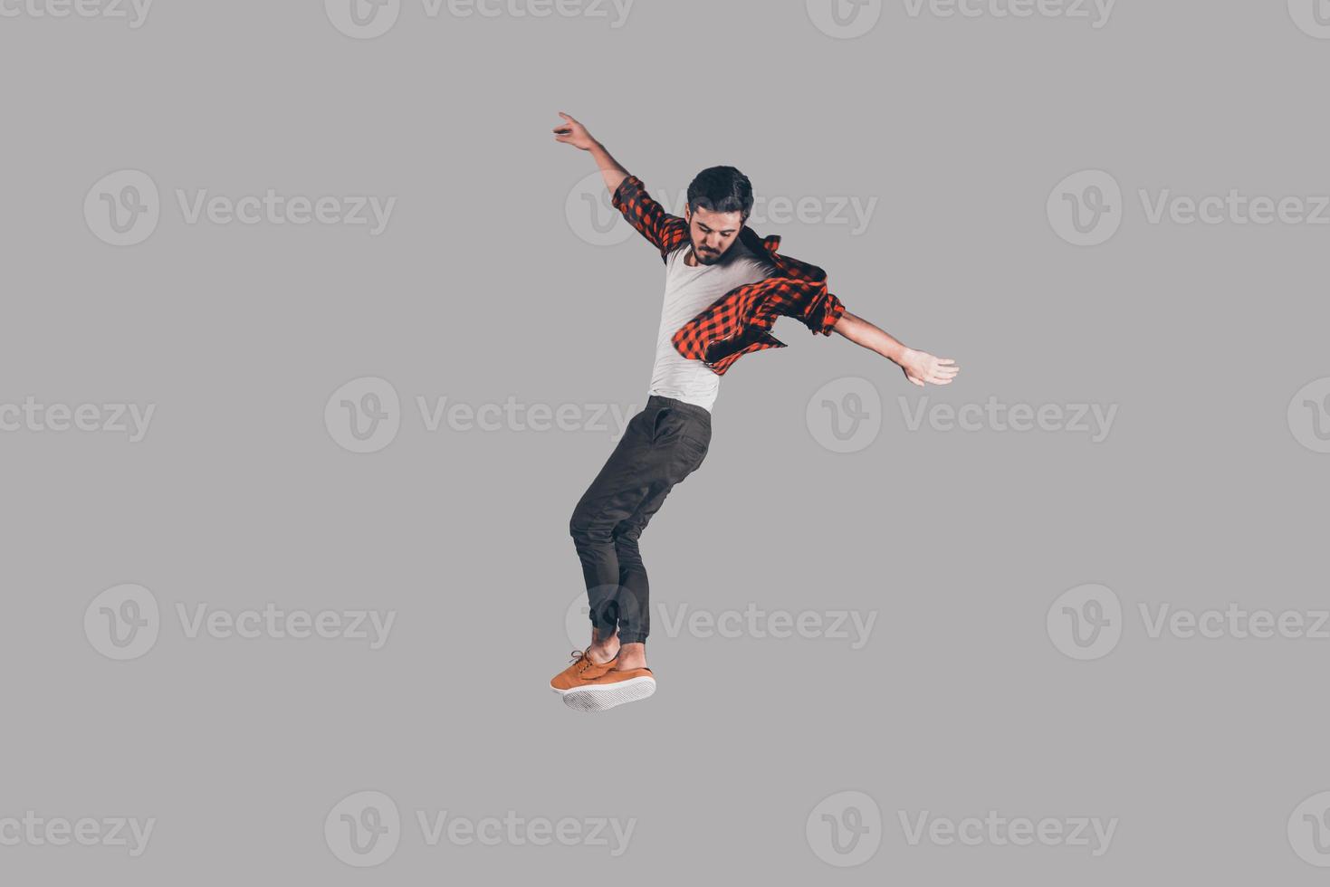 Feeling freedom in every move. Mid-air shot of handsome young man jumping and gesturing against background photo