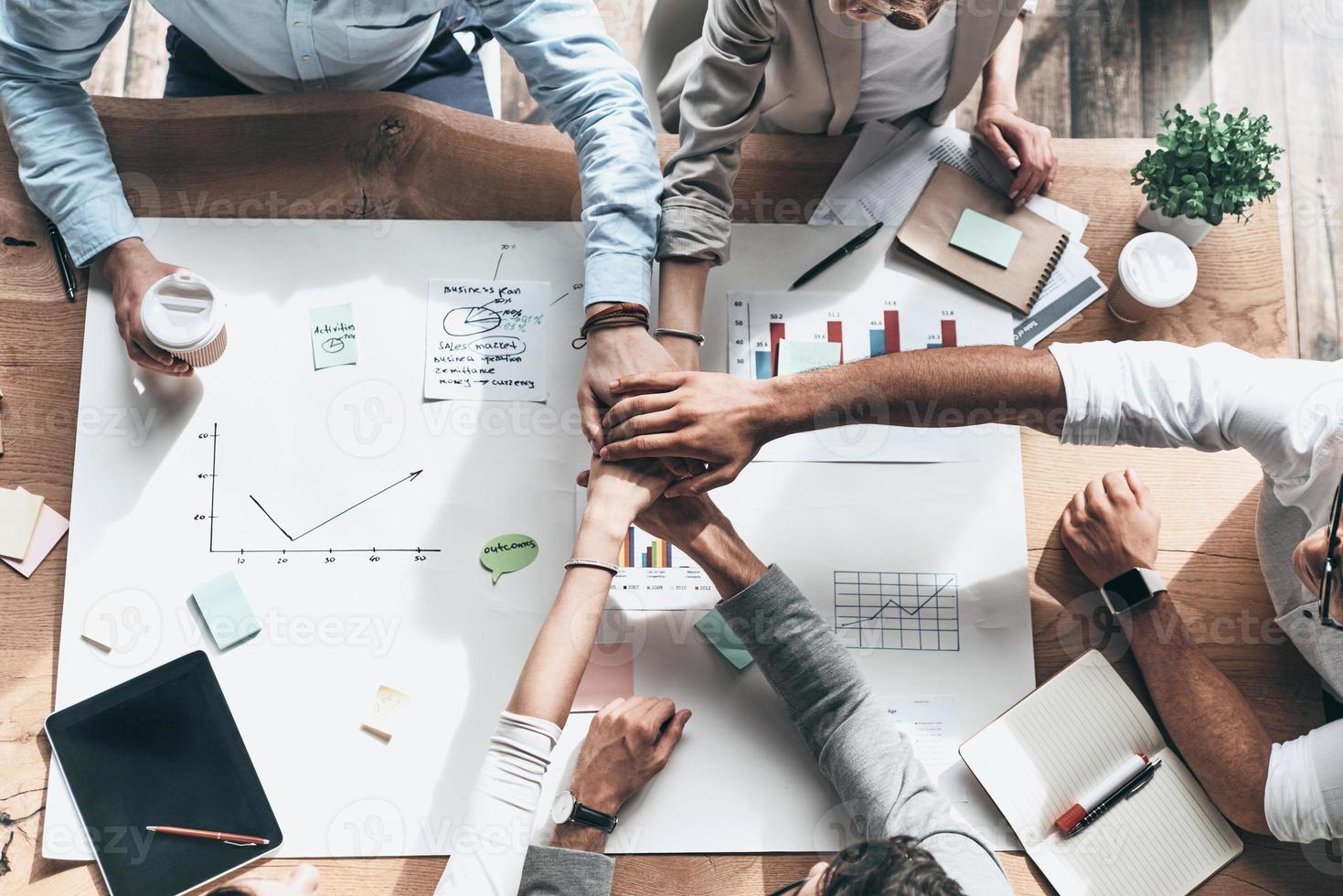 Successful team. Close up top view of business colleagues holding hands on top of one another in a symbol of unity while sitting in the creative office photo