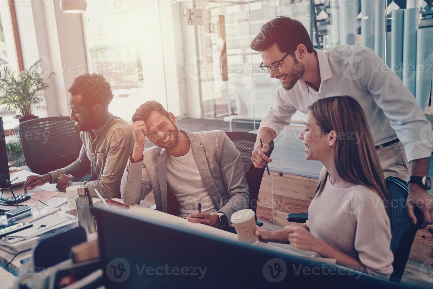Colleagues in smart casual wear communicating and using modern technologies while working in the office photo