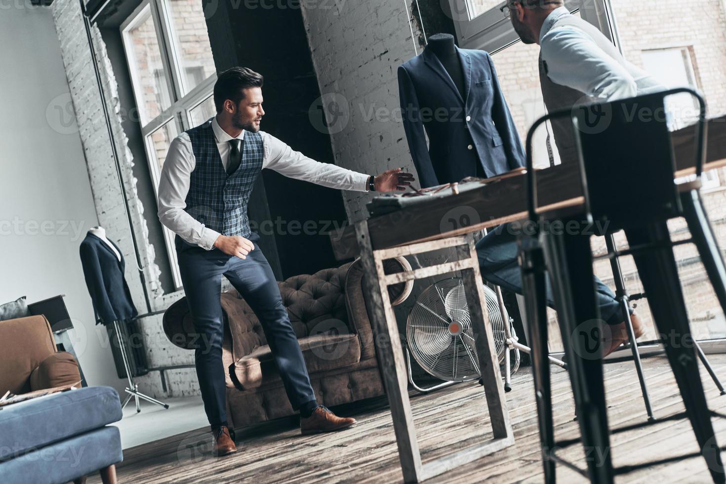 This is what I need. Two young fashionable men having a discussion while standing in workshop photo