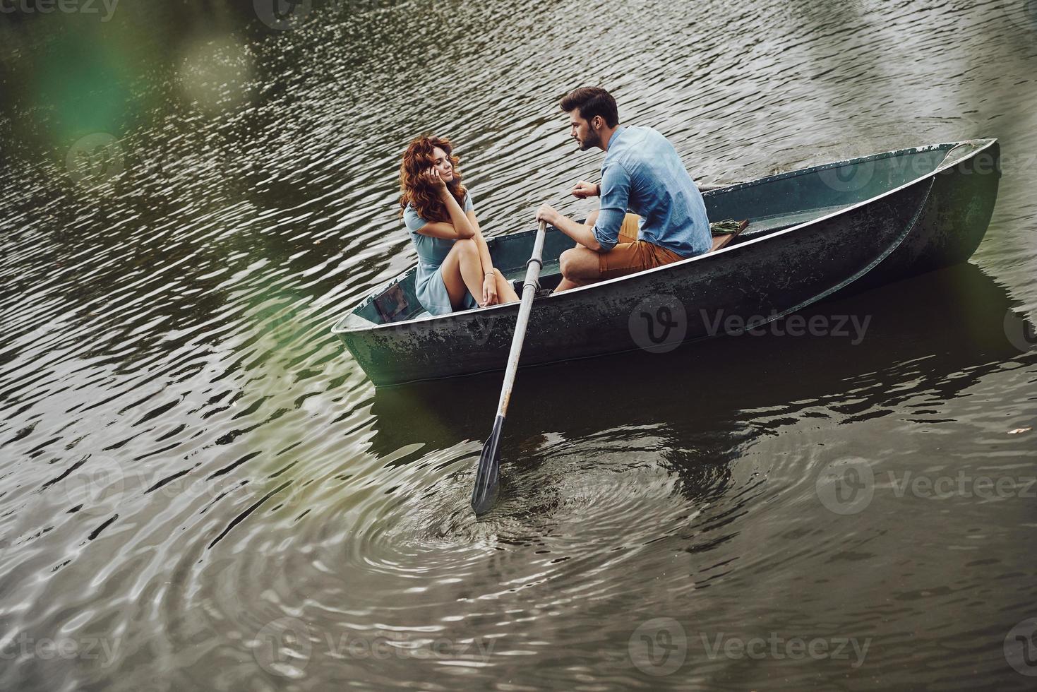 Fantastic way to spend the date. Top view of beautiful young couple enjoying romantic date while rowing a boat photo