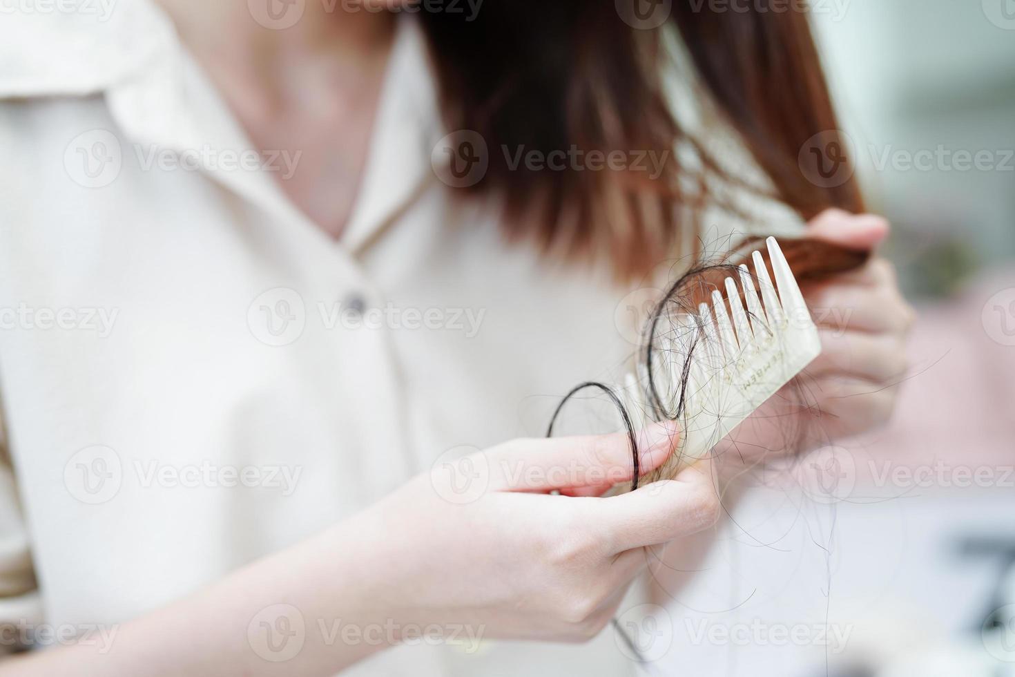 Asian woman have problem with long hair loss attach to comb brush. photo