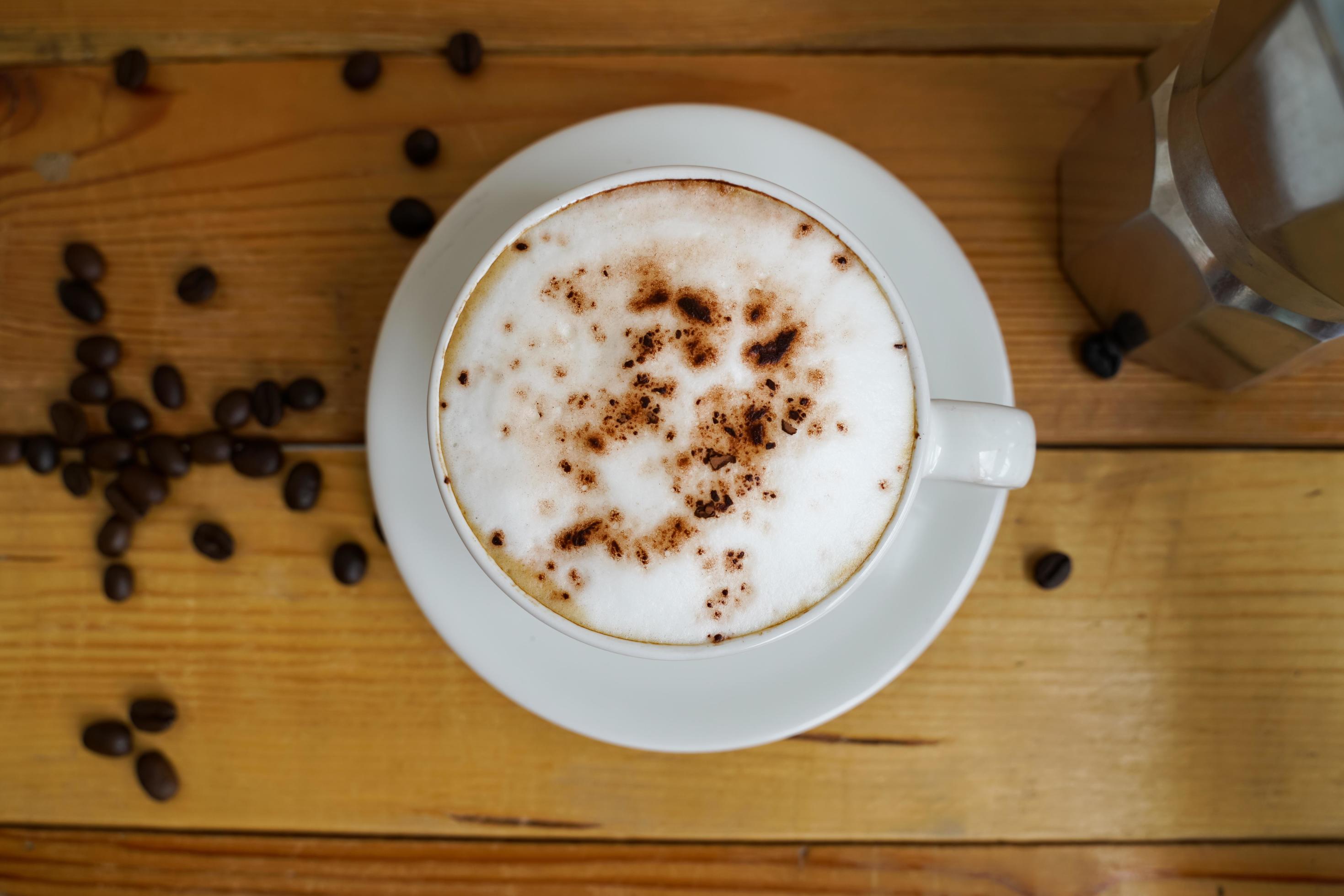 Hot cappuccino in white cup with wooden background,coffee is a popular