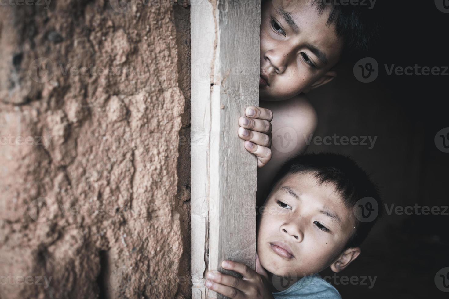 Closeup poor boy peeking out of a dilapidated house, Concept of assistance to the poor, human rights. photo