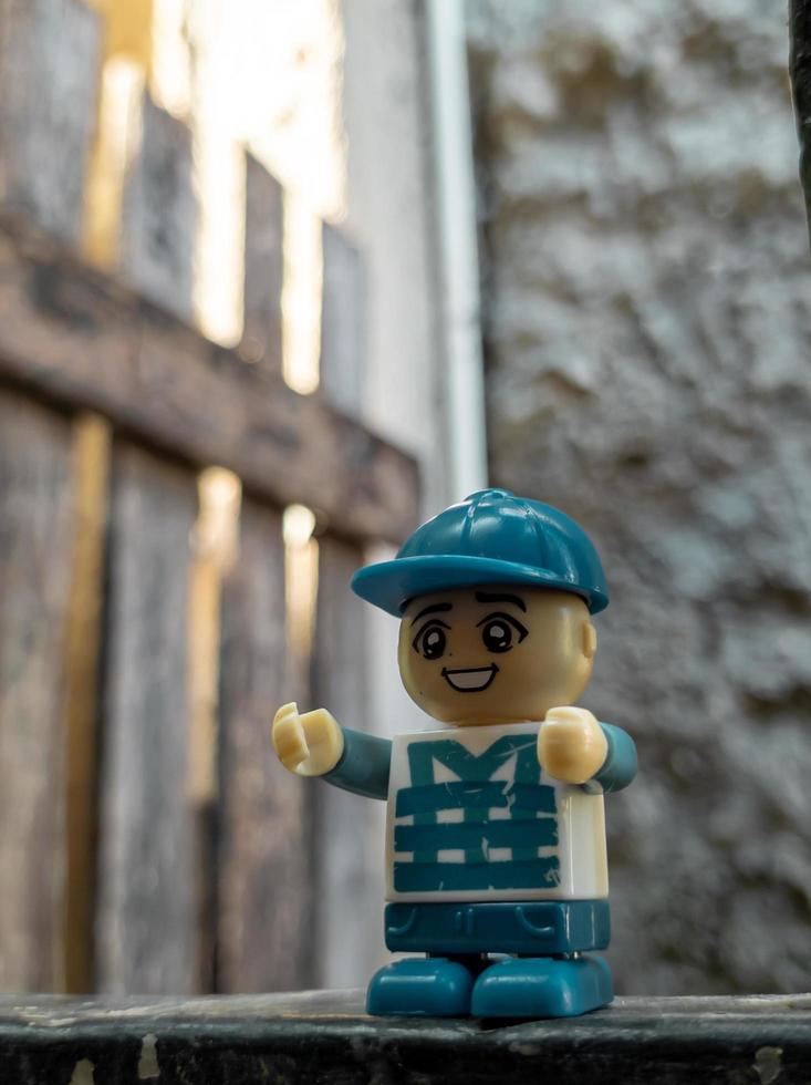 October 2022, Jakarta Indonesia, minifigure toy against a background of a blurred wall and a wooden fence in the sun photo